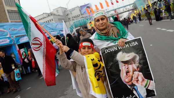 An Iranian woman holds a placard showing a caricature of US President Donald Trump being punched by a hand wearing a bracelet of the Iranian flag during a rally marking the anniversary of the 1979 Islamic revolution on February 10, 2017, in the capital Tehran - Sputnik International
