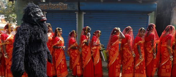 A performer dressed in a chimpanzee costume walks past brides as they arrive at a mass marriage ceremony in which, according to its organizers, 109 tribal, Muslim and Hindu couples from various villages across the state took their wedding vows, at Bahirkhand village, north of Kolkata, India February 5, 2017 - Sputnik International