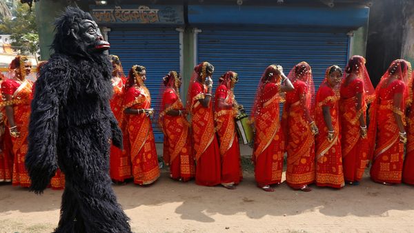  A performer dressed in a chimpanzee costume walks past brides as they arrive at a mass marriage ceremony in which, according to its organizers, 109 tribal, Muslim and Hindu couples from various villages across the state took their wedding vows, at Bahirkhand village, north of Kolkata, India February 5, 2017 - Sputnik International