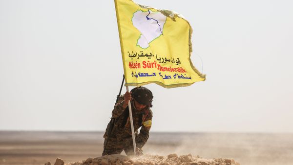 A member of the Syrian Democratic Forces (SDF), made up of US-backed Kurdish and Arab fighters, raises a flag of the SDF near the village of Bir Fawaz, 20 km north of Raqqa, during their offensive towards the Islamic State (IS) group's Syrian stronghold as part of the third phase retake the city and its surroundings, on February 8, 2017 A member of the Syrian Democratic Forces (SDF), made up of US-backed Kurdish and Arab fighters, raises a flag of the SDF near the village of Bir Fawaz, 20 km north of Raqqa, during their offensive towards the Islamic State (IS) group's Syrian stronghold as part of the third phase retake the city and its surroundings, on February 8, 2017 - Sputnik International