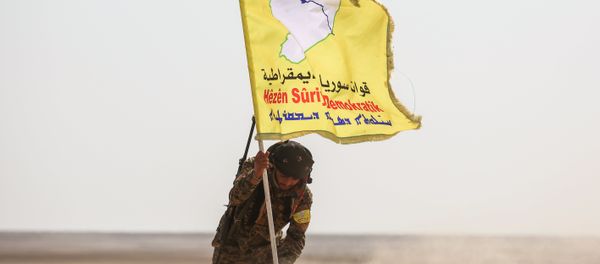 A member of the Syrian Democratic Forces (SDF), made up of US-backed Kurdish and Arab fighters, raises a flag of the SDF near the village of Bir Fawaz, 20 km north of Raqqa, during their offensive towards the Islamic State (IS) group's Syrian stronghold as part of the third phase retake the city and its surroundings, on February 8, 2017 - Sputnik International