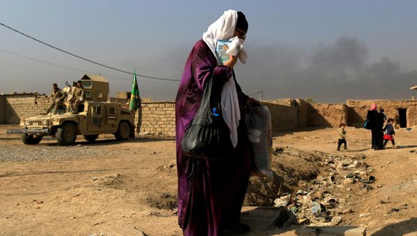A woman who is fleeing the fighting between Islamic State and the Iraqi army in the Intisar district of eastern Mosul, walks past a military humvee while heading to safer territory in Iraq November 7, 2016. - Sputnik International