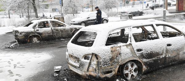 A policeman investigates a burnt car in the Rinkeby suburb outside Stockholm, Sweden February 21, 2017 - Sputnik International