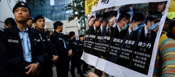 Police (L) stand guard as pro-democracy supporters (R) chant slogans and hold placards after the arrival of the seven police officers (pictured in placard on right), who were found guilty on February 14 of assaulting activist Ken Tsang during the 2014 pro-democracy protests, outside the District Court in Hong Kong on February 17, 2017 - Sputnik International