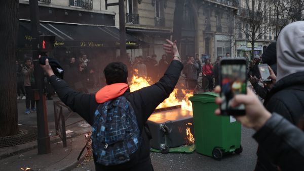 A young man gestures in front of burning dustbins which obstruct the street, during a protest of students against police brutality, following the alleged rape of Theo, next to the Lycee Voltaire secondary school in Paris, on February 23, 2017 A young man gestures in front of burning dustbins which obstruct the street, during a protest of students against police brutality, following the alleged rape of Theo, next to the Lycee Voltaire secondary school in Paris, on February 23, 2017 - Sputnik International