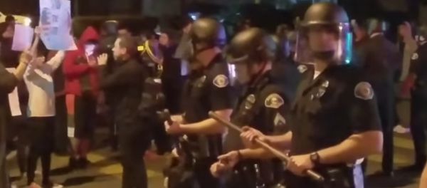 Police stand guard as demonstrators protests an off-duty LAPD officers firing his weapon at an unarmed teenage boy. - Sputnik International
