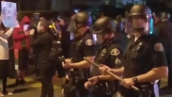 Police stand guard as demonstrators protests an off-duty LAPD officers firing his weapon at an unarmed teenage boy. - Sputnik International