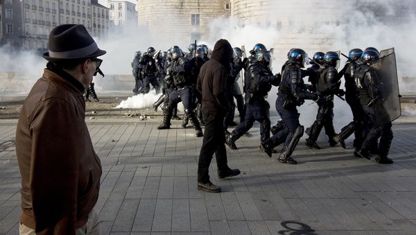 A man looks at riot police throwing tear gas while protesters demonstrate against the visit of French presidential election candidate for the far-right Front National (FN) party, on February 25, 2017 in Nantes, western France. - Sputnik International