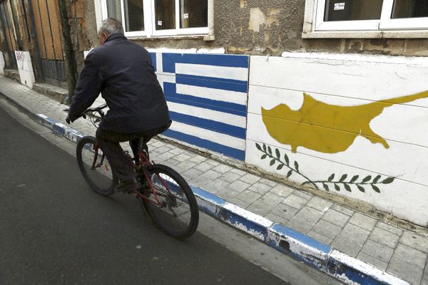 A man passes with a bicycle outside of a Greek Cypriot guard post with Cyprus', right, and Greece' flags painted on the wall in central divided capital Nicosia in the eastern Mediterranean island of Cyprus, on Thursday, Feb. 16, 2017 A man passes with a bicycle outside of a Greek Cypriot guard post with Cyprus', right, and Greece' flags painted on the wall in central divided capital Nicosia in the eastern Mediterranean island of Cyprus, on Thursday, Feb. 16, 2017 - Sputnik International