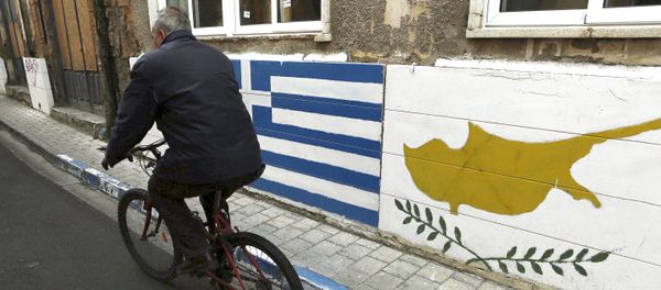 A man passes with a bicycle outside of a Greek Cypriot guard post with Cyprus', right, and Greece' flags painted on the wall in central divided capital Nicosia in the eastern Mediterranean island of Cyprus, on Thursday, Feb. 16, 2017 - Sputnik International