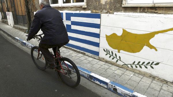 A man passes with a bicycle outside of a Greek Cypriot guard post with Cyprus', right, and Greece' flags painted on the wall in central divided capital Nicosia in the eastern Mediterranean island of Cyprus, on Thursday, Feb. 16, 2017 - Sputnik International