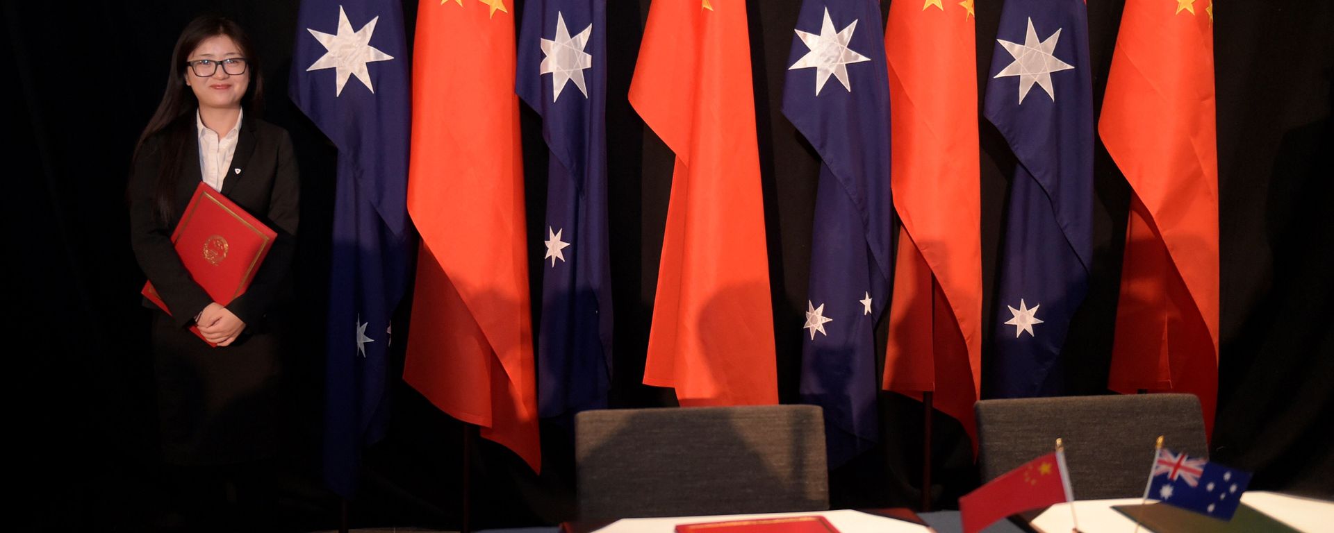 A woman holding a copy of the free trade agreement (FTA) stands next to national flags of China and Australia (File) - Sputnik International, 1920, 08.07.2022