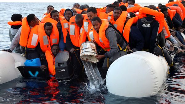 Sub-saharan migrants are seen aboard an overcrowded raft, as one of them uses a bucket to remove water from the raft, during a rescue operation by the Spanish NGO Proactiva Open Arms in the central Mediterranean Sea, north of the coastal Libyan city of Sabratha, February 3, 2017 - Sputnik International