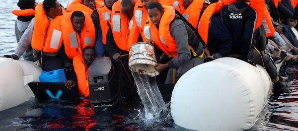 Sub-saharan migrants are seen aboard an overcrowded raft, as one of them uses a bucket to remove water from the raft, during a rescue operation by the Spanish NGO Proactiva Open Arms in the central Mediterranean Sea, north of the coastal Libyan city of Sabratha, February 3, 2017 - Sputnik International