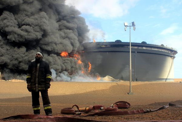 A Libyan fireman stands in front of smoke and flames rising from an oil storage tank at an oil facility in northern Libya's Ras Lanouf region on January 23, 2016, after it was set ablaze earlier in the week following attacks launched by Islamic State (IS) group jihadists to seize key port terminals. A Libyan fireman stands in front of smoke and flames rising from an oil storage tank at an oil facility in northern Libya's Ras Lanouf region on January 23, 2016, after it was set ablaze earlier in the week following attacks launched by Islamic State (IS) group jihadists to seize key port terminals. - Sputnik International
