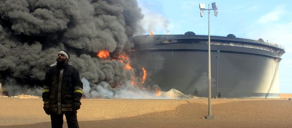 A Libyan fireman stands in front of smoke and flames rising from an oil storage tank at an oil facility in northern Libya's Ras Lanouf region on January 23, 2016, after it was set ablaze earlier in the week following attacks launched by Islamic State (IS) group jihadists to seize key port terminals. A Libyan fireman stands in front of smoke and flames rising from an oil storage tank at an oil facility in northern Libya's Ras Lanouf region on January 23, 2016, after it was set ablaze earlier in the week following attacks launched by Islamic State (IS) group jihadists to seize key port terminals. - Sputnik International