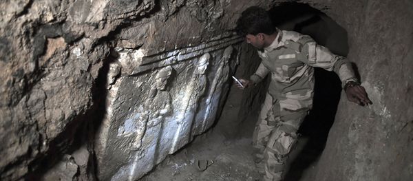 A member of the Iraqi troops stands next to archeological findings inside an underground tunnel in east Mosul on March 6, 2017 - Sputnik International