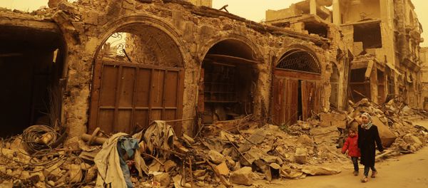 Syrian girls walk past destruction during a sandstorm in the once rebel-held Bab al-Nasr neighbourhood in the old part of Aleppo on March 10, 2017 - Sputnik International