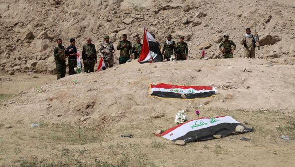 Iraqi security forces and allied Shiite militiamen pray at the site of a mass grave (file) - Sputnik International