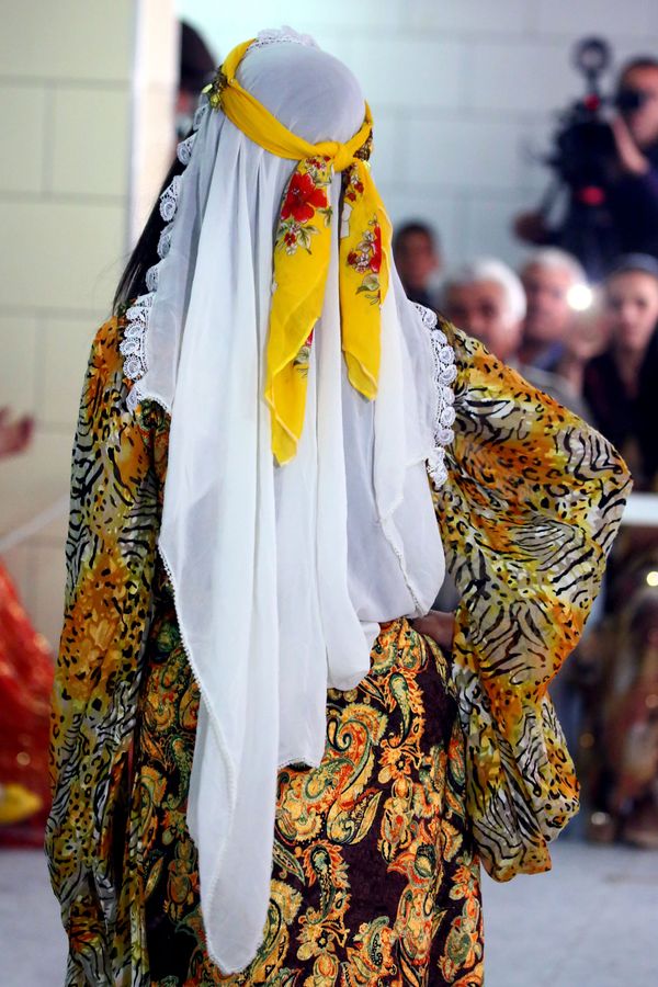 A Syrian-Kurdish female models traditional Kurdish attire consisting of a delicate gown and a white long headscarf with a yellow ribbon on top. A Syrian-Kurdish female models traditional Kurdish attire consisting of a delicate gown and a white long headscarf with a yellow ribbon on top. - Sputnik International