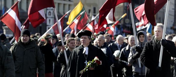 People hold flags, as they participate in the annual procession commemorating the Latvian Waffen-SS (Schutzstaffel) unit, also known as the Legionnaires, in Riga, Latvia March 16, 2017 - Sputnik International