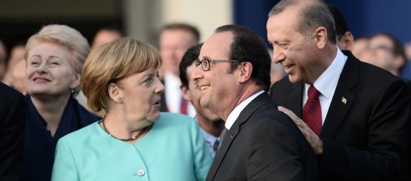 (L-R) German Chancellor Angela Merkel, French President Francois Hollande and Turkish President Recep Tayyip Erdogan share a smile as they attend the fly-past of NATO countries' jetfighters at the entrance of the National Stadium, the venue of the starting NATO summit, on July 8, 2016 - Sputnik International