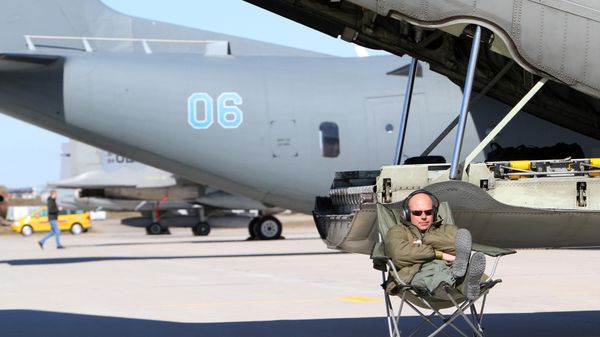 A technician sits near Sweden's C130 Hercules transport aircraft during the Lithuanian - NATO air force exercise at the air force base near Siauliai Zuokniai, Lithunaia on April 1, 2014 - Sputnik International