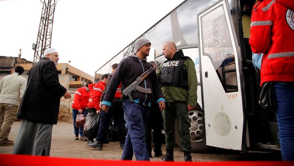 A rebel fighter walks with his weapon past a Syrian security personnel towards a bus to evacuate the besieged Waer district in the central Syrian city of Homs, after an agreement reached between rebels and Syria's army, Syria March 18, 2017 - Sputnik International