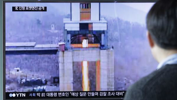 A man watches a TV news program showing an image that North Korea's Rodong Sinmun newspaper reports of a ground test of a new type of high-thrust rocket engine - Sputnik International