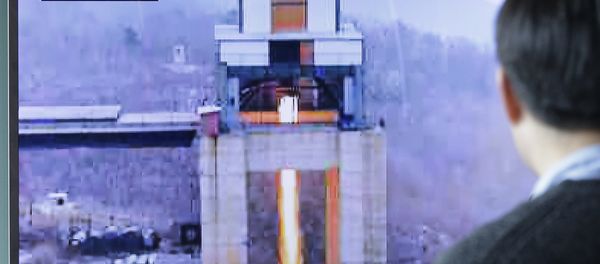 A man watches a TV news program showing an image that North Korea's Rodong Sinmun newspaper reports of a ground test of a new type of high-thrust rocket engine - Sputnik International