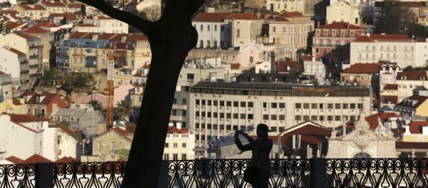 A woman taking pictures from a public garden is silhouetted against the buildings in Lisbon's old town center Wednesday evening, March 15, 2017. - Sputnik International