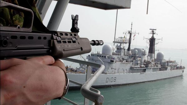 A UK Marine stands guard aboard the Royal Fleet Auxiliary forward repair ship Diligence ducked near to UK Royal Navy's destroyer Cardiff D108 - Sputnik International