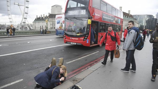 A woman assist an injured person after an incident on Westminster Bridge in London - Sputnik International