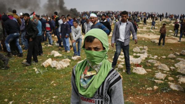 A young Palestinian protestor poses for a photo during clashes with Israeli security forces following a demonstration against Jewish settlements in village of al-Mughayyir, near the West Bank city of Ramallah, on March 24, 2017 A young Palestinian protestor poses for a photo during clashes with Israeli security forces following a demonstration against Jewish settlements in village of al-Mughayyir, near the West Bank city of Ramallah, on March 24, 2017 - Sputnik International
