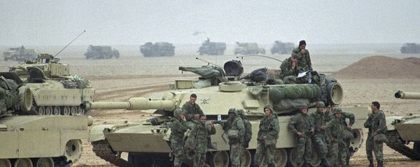 Troops from the Army’s 1st Infantry Division lean on an M1A1 Abrams main battle tank as a convoy passes in the background at an assembly point in afternoon on Sunday, Jan. 21, 1991 in Saudi Arabia. Troops from the 1st Infantry Division have taken up positions close to the border with Kuwait Troops from the Army’s 1st Infantry Division lean on an M1A1 Abrams main battle tank as a convoy passes in the background at an assembly point in afternoon on Sunday, Jan. 21, 1991 in Saudi Arabia. Troops from the 1st Infantry Division have taken up positions close to the border with Kuwait - Sputnik International