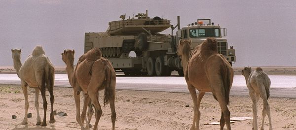 (FILES) A flat-bed truck carrying a US M-1A Abrams tank passes a group of camels in this file photo taken 03 February 1991 in the Saudi Arabian desert - Sputnik International