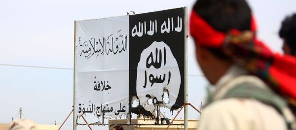 Members of the US-backed Syrian Democratic Forces (SDF), made up of an alliance of Arab and Kurdish fighters, stand under an Islamic State (IS) group banner in the recently recaptured town of Al-Karamah, 26 kms from the IS bastion of Raqa, as they advance to encircle the jihadists, on March 26, 2017 - Sputnik International