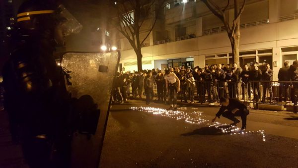 Youths use candles to write the word Violence in the road in front of a line of riot police outside the commisariat of the 19th Arrondissement (District) of Paris late on March 27, 2017, during clashes in the wake of the death of a Chinese national during a police intervention. Youths use candles to write the word Violence in the road in front of a line of riot police outside the commisariat of the 19th Arrondissement (District) of Paris late on March 27, 2017, during clashes in the wake of the death of a Chinese national during a police intervention. - Sputnik International