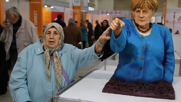 A visitor takes a picture next to the cake bust of German Chancellor Angela Merkel by Turkish confectioner Tuba Geçkil at the Festival of Chocolates, Sweets and Cakes in Istanbul. A visitor takes a picture next to the cake bust of German Chancellor Angela Merkel by Turkish confectioner Tuba Geçkil at the Festival of Chocolates, Sweets and Cakes in Istanbul. - Sputnik International