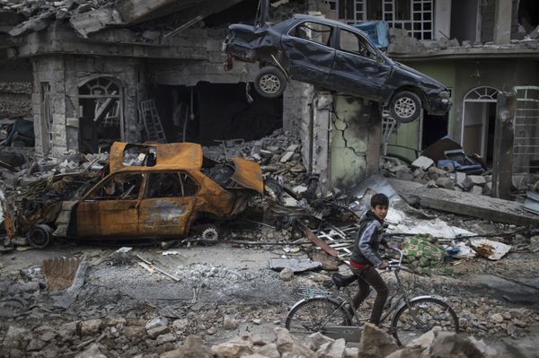 A boy rides his bike past destroyed cars and houses in a neighborhood recently liberated by Iraqi security forces, on the western side of Mosul, Iraq, Sunday, March 19, 2017 - Sputnik International