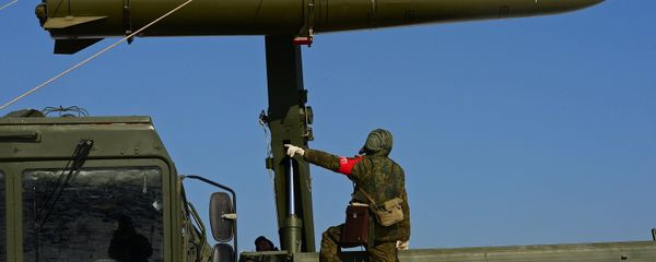 A Russian soldier watches a transporter-loader place an Iskander-M shorter-range missile onto a self-propelled launcher during an exercise involving missile and artillery units of the Eastern Military District's Fifth Russian Army in the Primorye Territory - Sputnik International