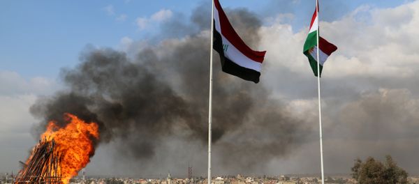 The Kurdish and Iraqi flag sway in the wind as a bonfire burns during the Noruz spring festival celebrations in the northern city of Kirkuk, about 240 kilometres (150 miles) north of Baghdad on March 20, 2017 - Sputnik International