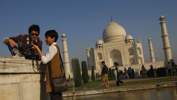 Tourists look at their camera after taking a picture near the UNESCO World Heritage site Taj Mahal in Agra - Sputnik International