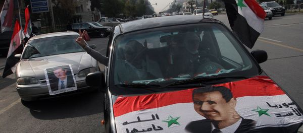 Syrians display national flags and banners with photos of Syrian President Bashar Assad during a pro-government event in Damascus, Syria. (File) - Sputnik International