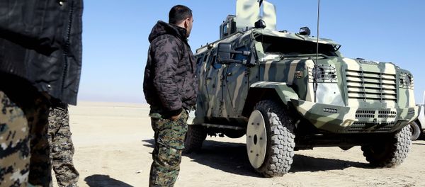 A fighter from the Syrian Democratic Forces, inspects a military vehicle supplied by the US-led coalition, as they gather near a village north-east of Raqa - Sputnik International