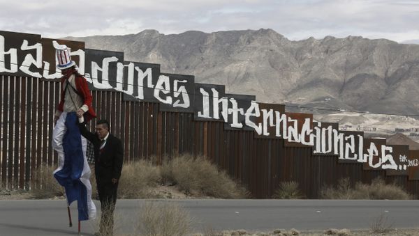 Protestors dressed as a diabolical Uncle Sam, on stilts, and Mexico's President Enrique Pena Nieto hold hands as they walk along the border fence in Ciudad Juarez, Mexico Sunday, Feb. 26, 2017. - Sputnik International