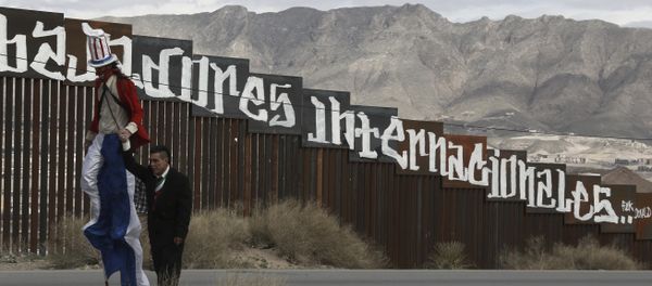Protestors dressed as a diabolical Uncle Sam, on stilts, and Mexico's President Enrique Pena Nieto hold hands as they walk along the border fence in Ciudad Juarez, Mexico Sunday, Feb. 26, 2017. - Sputnik International