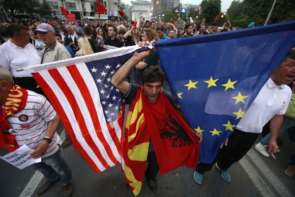 A protestor holds the flags of the United States, Macedonia, Albania and the European Union while attending a march through downtown Skopje, Macedonia, Monday, April 18, 2016 - Sputnik International