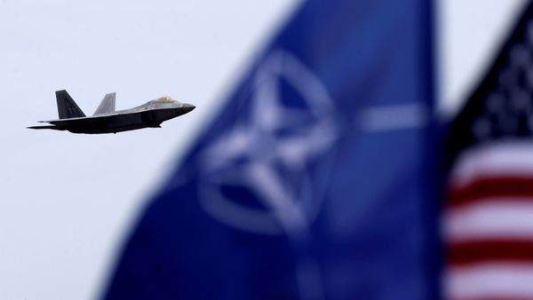 NATO and US flags flutter as U.S. Air Force F-22 Raptor fighter flies over the military air base in Siauliai, Lithuania, April 27, 2016. - Sputnik International