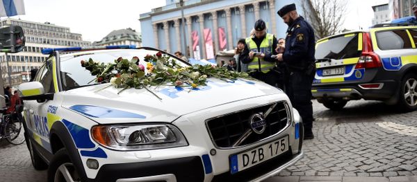 Flowers lay on a police car at Hotorget square near the crime scene in central Stockholm on April 8, 2017, the day after a hijacked beer truck plowed into pedestrians on Drottninggatan and crashed into Ahlens department store, killing four people, injuring 15 others Flowers lay on a police car at Hotorget square near the crime scene in central Stockholm on April 8, 2017, the day after a hijacked beer truck plowed into pedestrians on Drottninggatan and crashed into Ahlens department store, killing four people, injuring 15 others - Sputnik International